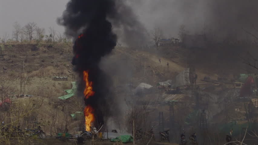 Uncontrolled fire burning at an unregulated oil well producing thick black smoke and pollution