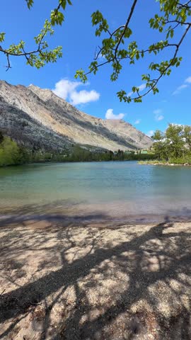 Person filming a beautiful mountain lake with crystal clear water in Waterton National Park in Alberta, Canada