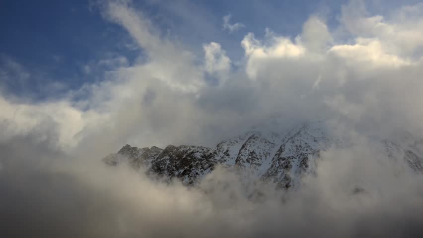 Snow capped mountain peaks emerging from clouds