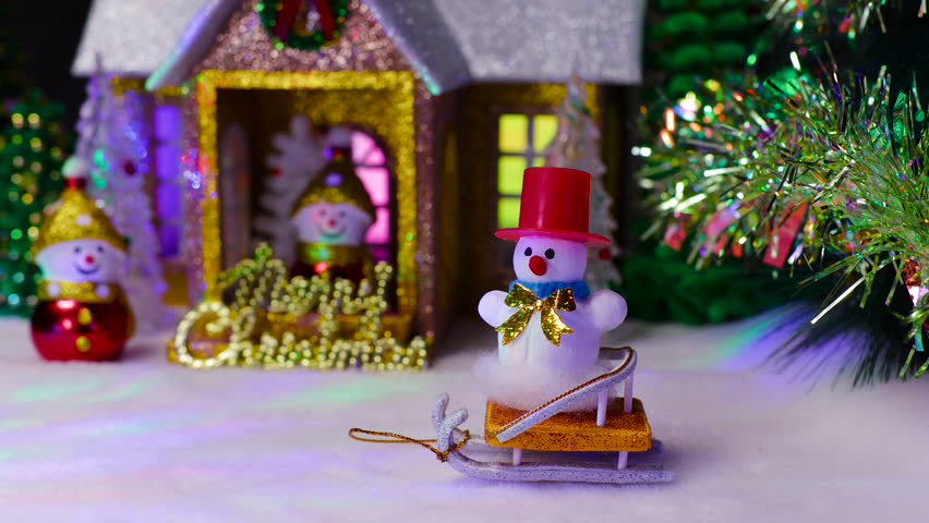 A beautiful house with two snowmen on the porch and next to it and a snowman on a sled in front