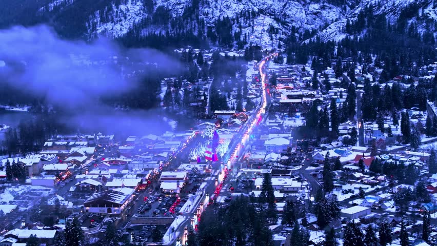 Snowy town at night with lights and houses in winter landscape.