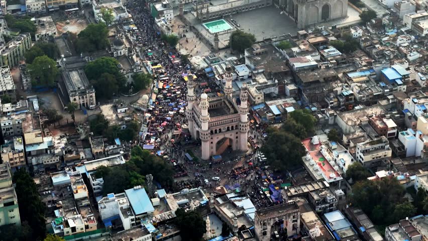 Cinematic aerial view of Charminar and Mecca Masjid surrounded by densely packed streets, vibrant bazaars, and massive crowds, capturing the historic and cultural heartbeat of Hyderabad’s old city.