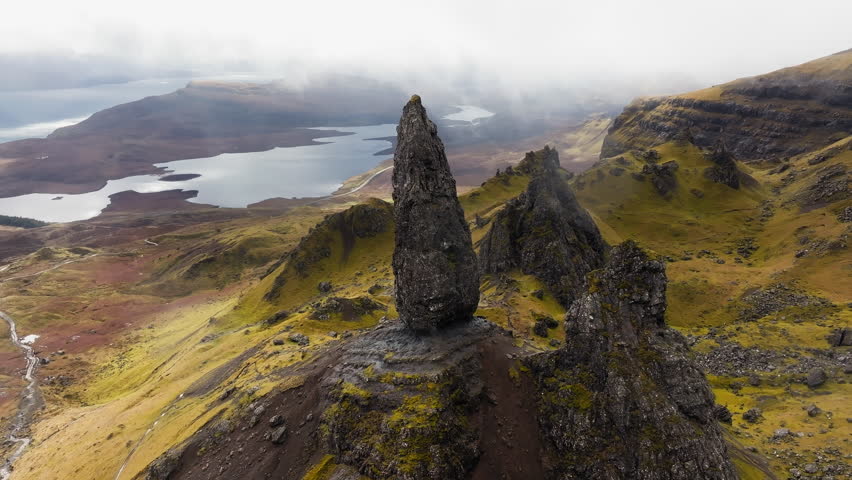 Tall rock pinnacle and rugged hills at The Storr on Isle of Skye Scotland aerial ascend tilt down