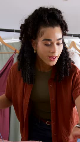 Vertical video: Taking blue tape woman checking pink cloth in studio cutting with shears for sewing. Fabric, measuring, scissors, tailoring, garment, dress, vertical video