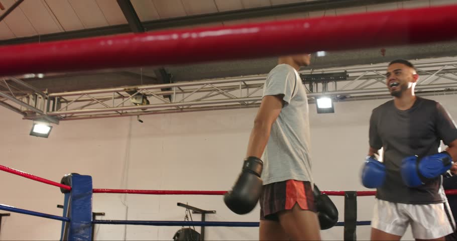 Stepping into boxing ring, two male sparring partners exchanging jabs and crosses during training. Athletic, combat, determined, training, strength, dynamic, performance