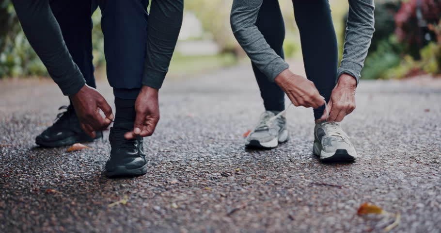 Fitness, nature and couple tying laces for workout, training or running outdoor in park for wellness. Sports, sneakers and hands of people preparing for cardio exercise, health or active in morning.