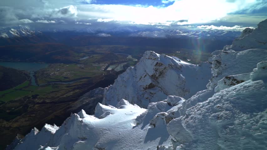 Look out The Remarkables Ski Resort winter jagged snowy covered peaks Rock face New Zealand Lake Wakatipu Queenstown Frankton lush green valley morning sunny blue sky clouds landscape pan left