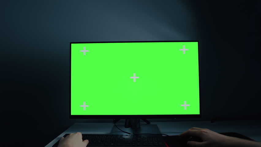 Computer monitor with green screen in dark workspace