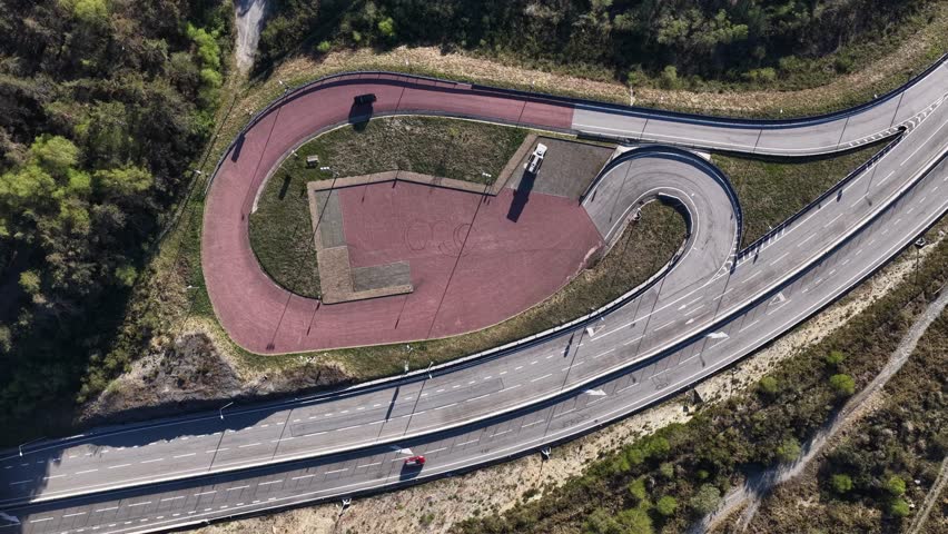 Aerial view of winding roads surrounding a red paved area with buildings contrasting the green trees, Vila Real, Portugal.