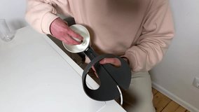 Close-up video of a person's hands screwing a new LED light bulb into a modern, minimalist grey desk lamp. Home improvement, DIY, and setup concept in a clean, contemporary setting. - Powered by Shutterstock - Get 15% off with code: PIKWIZARD15