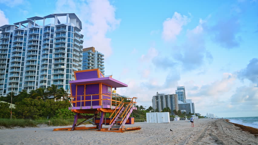Wooden lifeguard station on Miami Beach during daytime. Low angle shot of a wooden lifeguard hut on the beach with modern skyscrapers and ocean background.