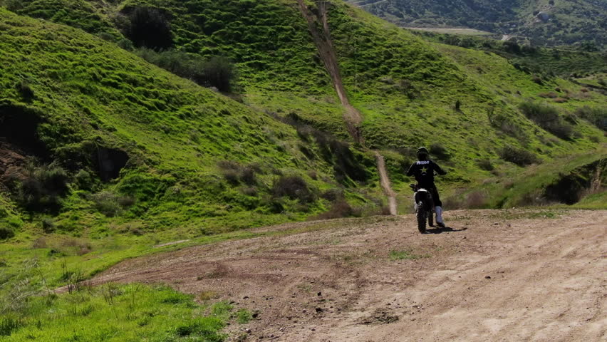 Extreme freestyle motocross athlete jumping with his motorcycle from a natural ramp in the mountains