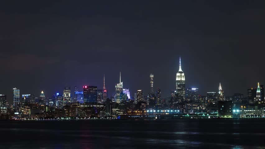 Night city skyline with illuminated buildings and river view.