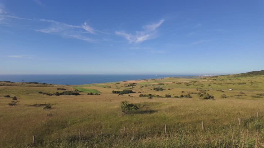 Scenic panoramic view of the rolling hills and coastline at Cap Blanc Nez, France, with the English Channel under a clear blue sky.