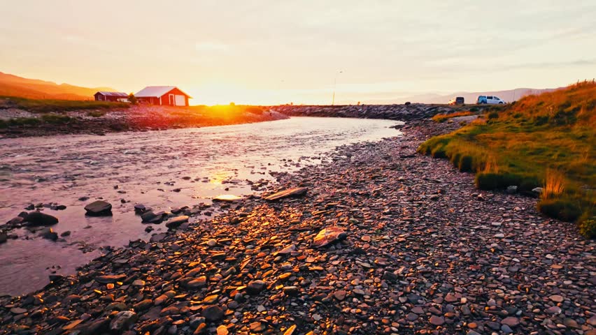 Kokelv, Hammerfest, Finnmark, Norway - The Sun Sets Behind a Red Cabin, Casting a Warm Glow Over the Rocky Shoreline and Fishing Pole - POV Shot