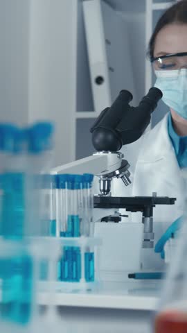 A dedicated scientist in a white lab coat examines samples under a microscope, surrounded by colorful test tubes, highlighting the significance of their meticulous research in the lab