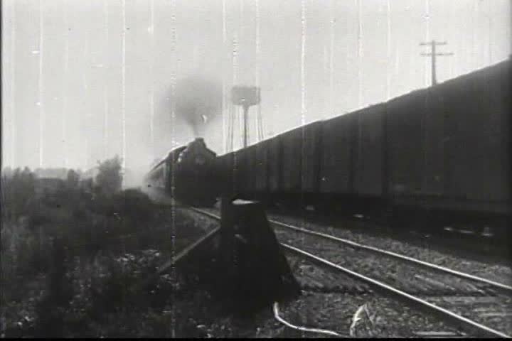 1920s - A train passes and we see street scenes in 1920s.