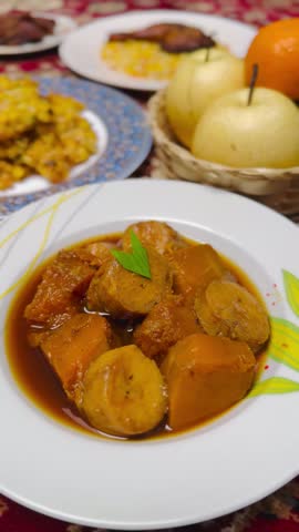 A portrait view of a plate of Kolak (Indonesian dessert) that consists of banana, pumpkin, pandan leaf, and palm sugar.