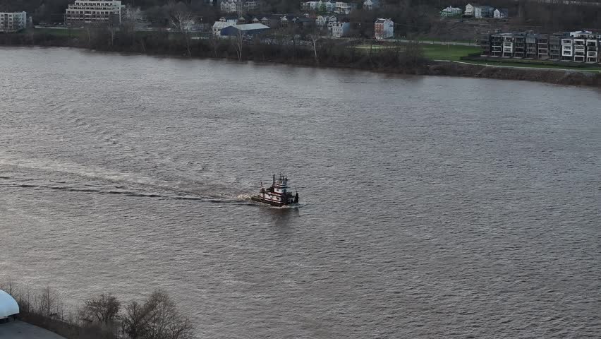 Aerial view of a boat moving along the river, the buildings on the riverbank are visible in the distance, Cincinnati, Ohio, United States.