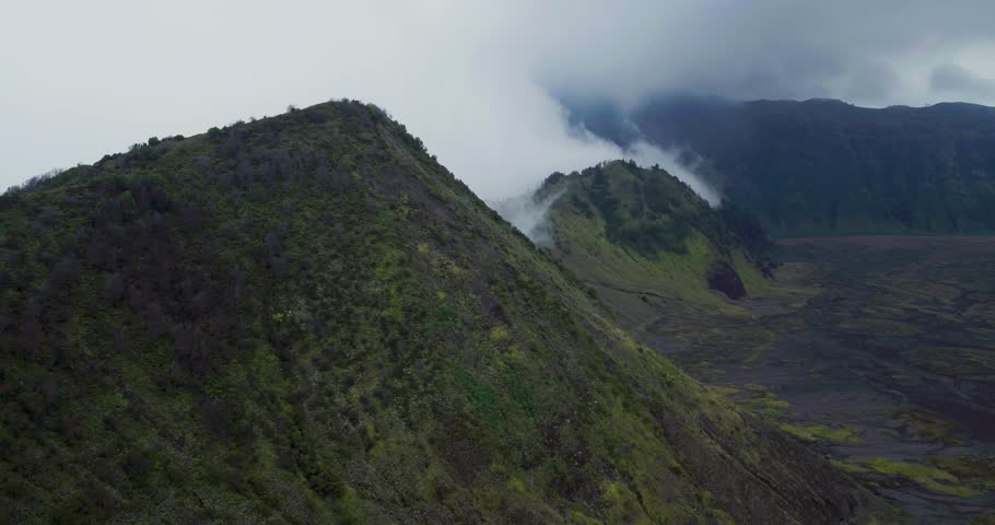 Aerial drone shot of Bromo volcano with fog covering the mountain landscape, creating a cinematic volcanic environment.