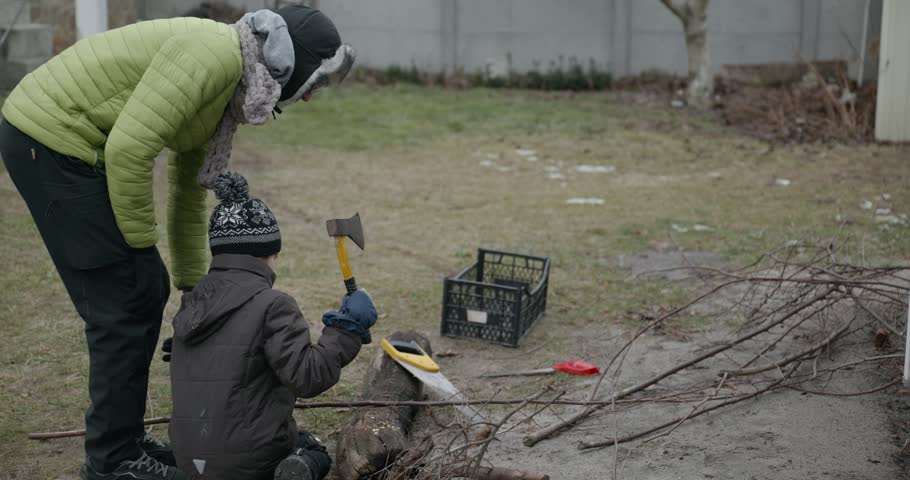 Men with kid cut branches in backyard and stockpile firewood in shed for winter. 4K 10-bit