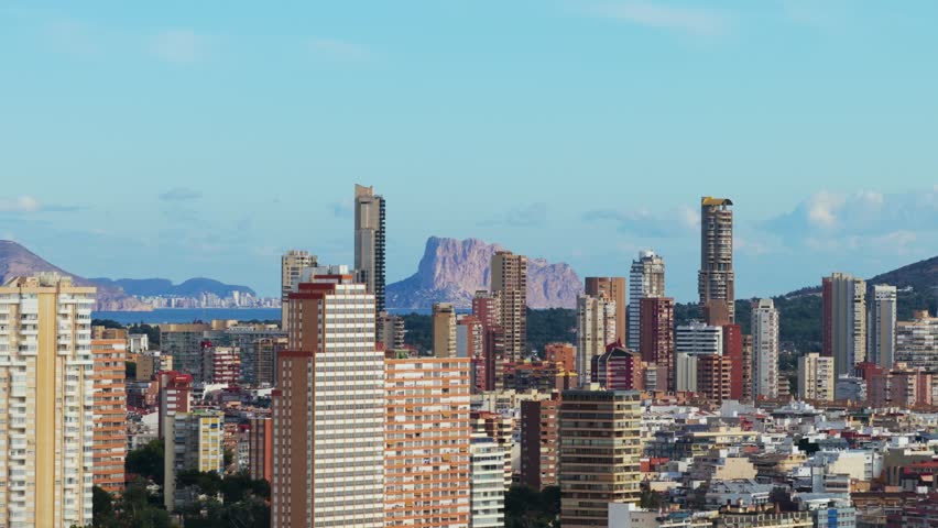Panoramic View Of Benidorm Skyline In Alicante, Spain, With Penon de Ifach Rock Formation In Background. drone sideways shot