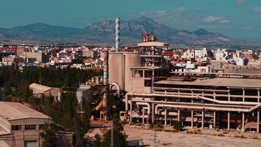 Abandoned cement factory complex near a suburban city with mountains in the background