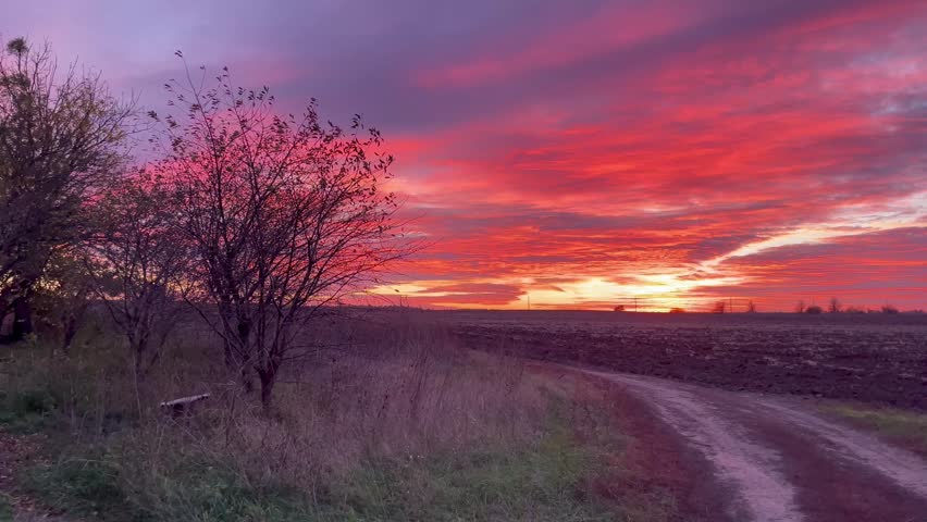 Beautiful purple and orange sunset sky over autumn farm landscape