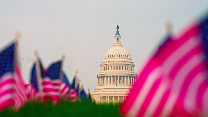 Capitol building national symbol patriotism. American flag waving at Capitol. Washington DC Capitol Hill landmark. United States Capitol iconic architecture.