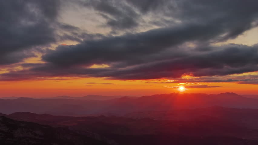 Sun setting over mountain with dramatic clouds. Beautiful evening sky at sunset, aerial view 4k