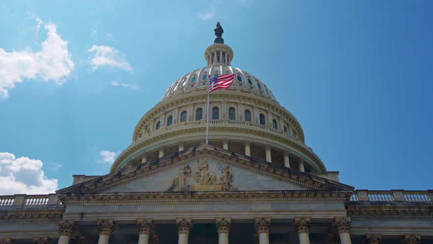 Capitol dome with American flag. Capitol monument in Washington DC. Historic capitol facade in sky. Patriotic capitol landmark.