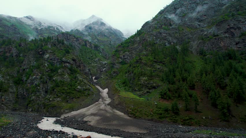 4K Aerial shot of raining in green mountains at Miyar Valley, Himachal Pradesh, India. Dark clouds above mountain peak during monsoon season. Nature landscape.