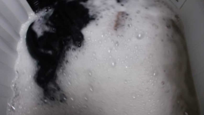 clothes being washed in washing machine with soap suds close up. HD video footage