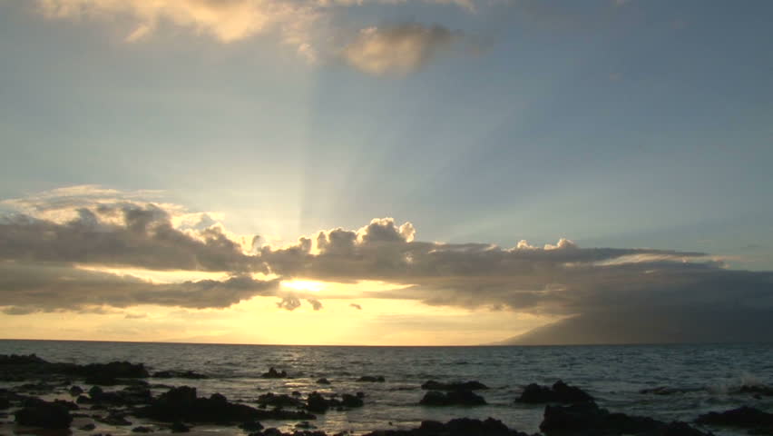 Sun going down over Pacific Ocean from rocky shoreline, time lapse.