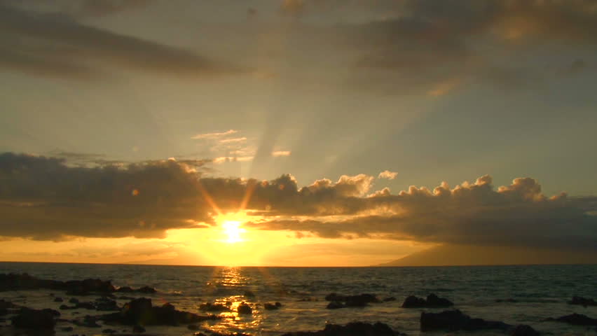 Sun rising over Pacific Ocean from rocky shoreline, time lapse.