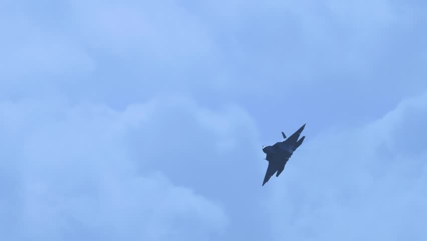 Fighter jet flying across a cloudy sky, military aircraft in motion.