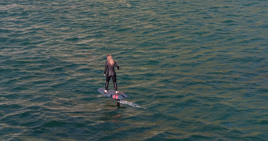 Ocean, active and woman on electric surfboard for fitness, workout or water sports on vacation. Travel, adventure and female person on efoil by sea for exercise, training or surfing on holiday.