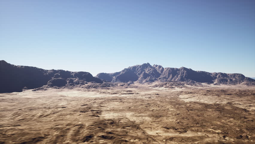 sunlit barren desert plain with mountains, wide cinematic drone sweep over cracked earth and rocky plateau, jagged distant peaks under clear blue sky, golden