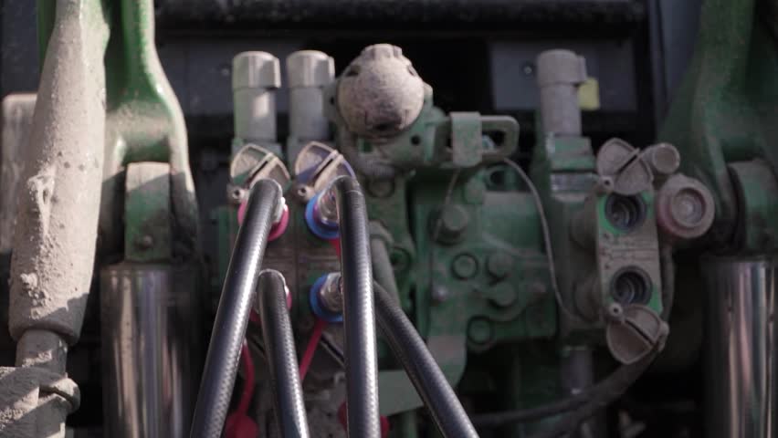 Connecting Hydraulic Hoses of Grader to Tractor
Farmer connecting hydraulic hoses of grader attachment to tractor. Farm equipment setup and agricultural machinery work.