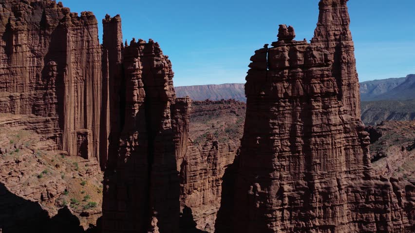 Fisher Towers showcasing dramatic red Cutler sandstone formations under a clear blue sky. Aerial Dolly Left