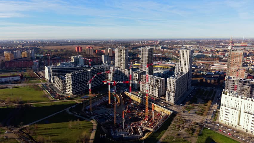 Aerial perspective of a large construction site in a modern city, featuring numerous tower cranes and new high-rise buildings. Cascina Merlata, Milan, Italy