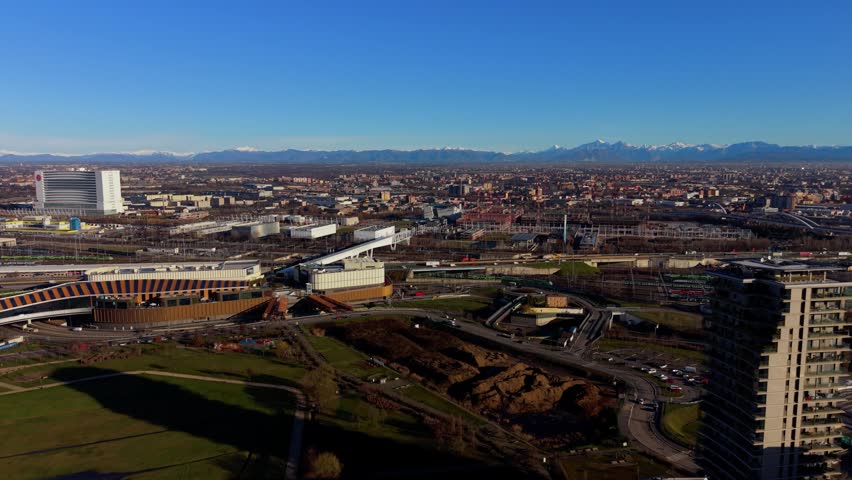 Expansive aerial panorama of turin, italy, featuring modern architecture, urban parks, and the majestic snow-capped alps on the horizon