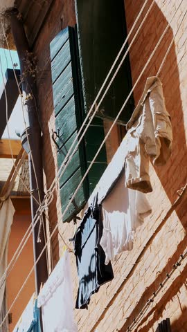 VENICE, ITALY : beautiful old architecture of Venice, a house with old green shutters, clothes are dried on clothesline. against the blue sky, on a hot summer day,