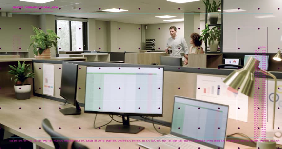 Woman and man entering with coffee, pausing at office desk, pointing at screens, reviewing report. Collaboration, teamwork, focus, productivity, openplan, workspace, monitors