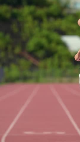 Morning jog, sporty woman runs at a stadium track on a sunny day, pro runner marathon daily training, slow motion moving forward, motivation.