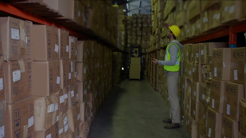 Warehouse worker scanning racks in aisle, initiating blue network overlay mapping shelf inventory. Storage, forklift, barcode, boxes, cardboard, hardhat, vest