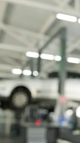 Blurred interior background of a modern, clean, and spacious automotive service station with car lifts and equipment.
