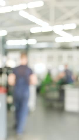 Blurred interior background of a modern, clean, and spacious automotive service station with car lifts and equipment.