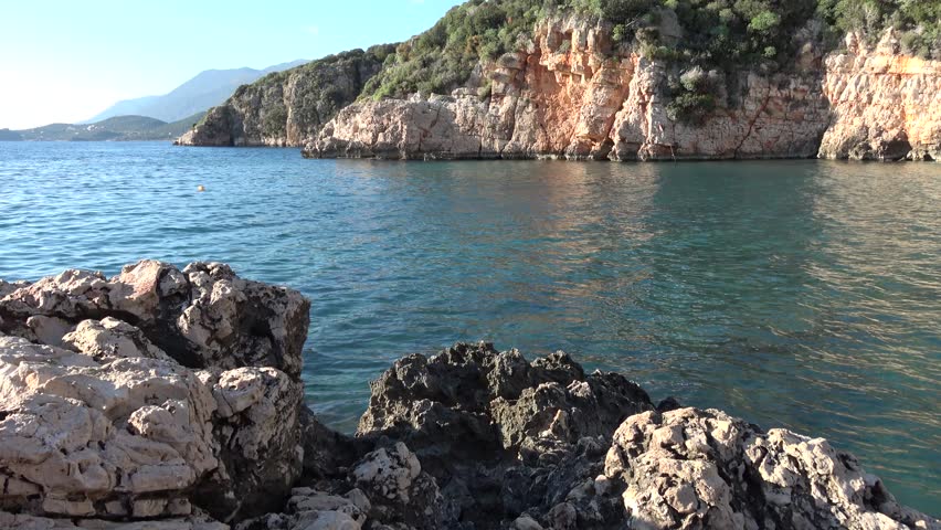 Kas, Turkey - 24 of February 2026: Rocks and turquoise sea water against high cliffs and blue sky
