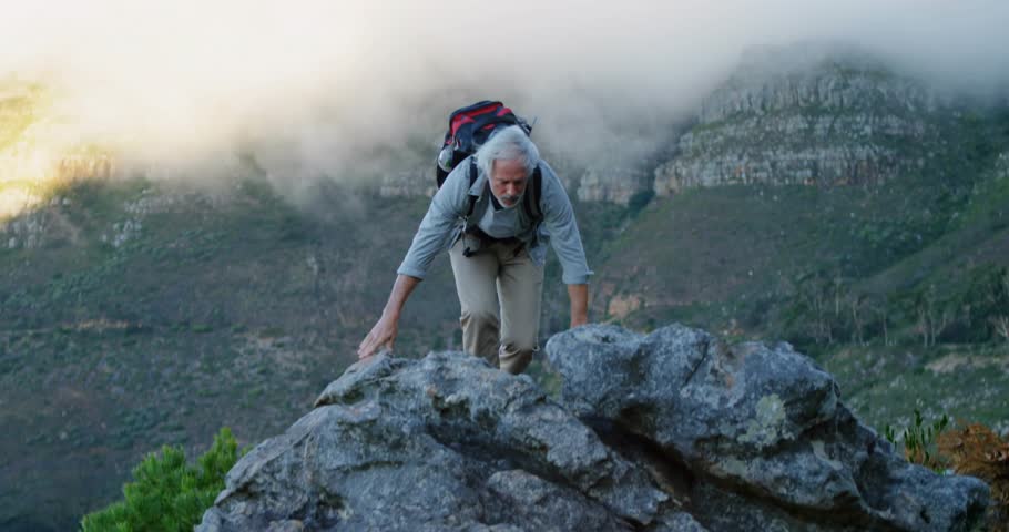Hiker pulling onto rock, rising, raising arms, cheering as social icons popping from left at waist. Ascent, summit, mountains, backpack, boots, mist, badges